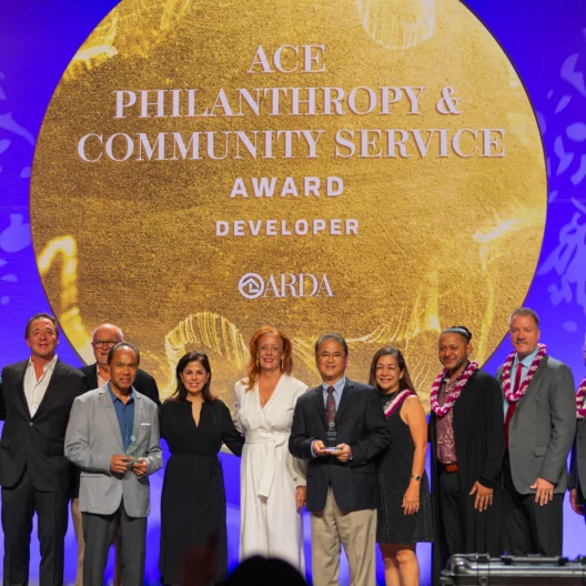 A group of people on stage at an awards ceremony, with a backdrop reading "ACE Philanthropy & Community Service Award.